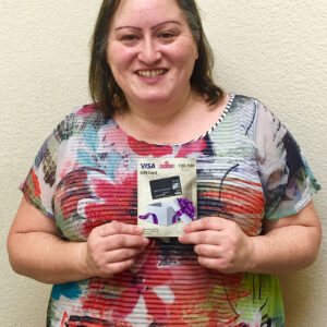 A woman smiles and holds a VISA gift card with a value of $20-500, possibly representing a settlement received from a personal injury case in Las Vegas.
