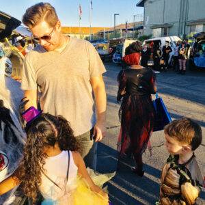 A father and daughter enjoy a safe and fun Halloween "trunk or treat" event in Las Vegas, highlighting community and family safety, with reminders of personal injury awareness.