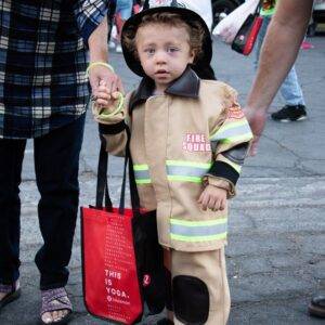 A young child dressed as a firefighter, symbolizing safety and protection, holds hands with an adult in Las Vegas, representing the firm's commitment to safeguarding the community and advocating for those injured due to negligence.