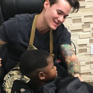 Young boy getting a haircut from a friendly barber, representing the community and care a Las Vegas personal injury law firm offers to protect the future of children and families affected by accidents.