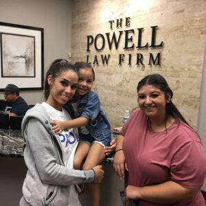 A family stands smiling in the welcoming lobby of The Powell Law Firm, ready to assist with personal injury cases in Las Vegas.