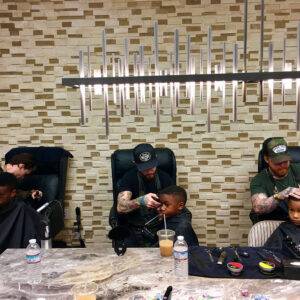 Image depicts three young children receiving haircuts from professional barbers in a stylish Las Vegas barber shop, an illustration of personal care and attention to detail.