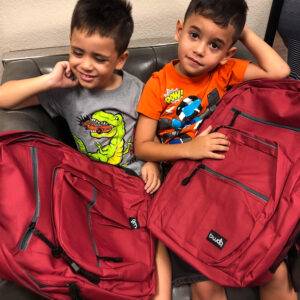 Two young boys with backpacks, sitting on a couch, possibly representing families impacted by personal injury in Las Vegas.
