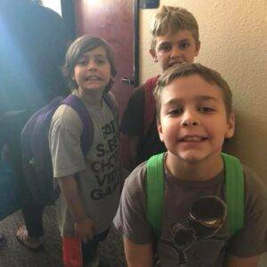 Three young boys with backpacks stand smiling, representing the importance of child safety and the personal injury services a Las Vegas law firm offers to protect families.