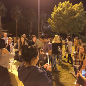 A group of diverse people in Las Vegas hold candles at a night vigil, possibly remembering those affected by personal injury or loss, symbolizing support and solidarity.