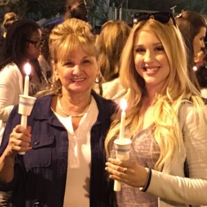Two women holding candles at a vigil in Las Vegas, representing hope and healing after a personal injury, with the crowd in the background.