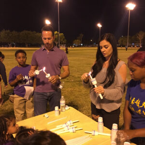A diverse group in Las Vegas gathers at night to light candles at a vigil, symbolizing support and remembrance for personal injury victims in the community.