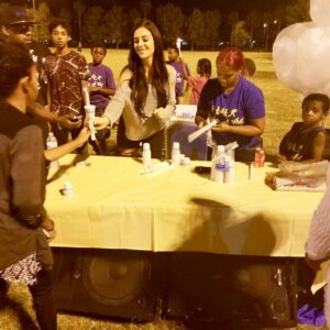 A Las Vegas personal injury law firm sponsors a candlelight vigil in a park, with community members gathering at a table to receive candles in remembrance of personal injury victims.