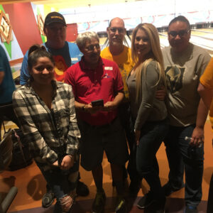 A group of diverse people smile at the camera while at a bowling alley in Las Vegas; image could represent a personal injury law firm team outing.
