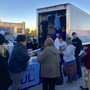 Group of people receiving food donations from a Las Vegas Personal Injury Law Firm truck, showing the firm's community involvement.