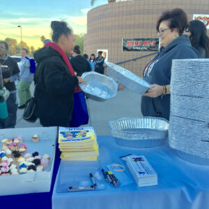 Outdoor event with people, cupcakes, aluminum trays, safety brochures and KOMP 92.3 radio station signage.