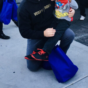 A heartwarming image of a Las Vegas lawyer kneeling with a child waving, showcasing community involvement and support in personal injury cases.
