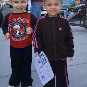 Two smiling children, possibly injured, holding a flyer for YMCA preschool in Las Vegas, suggesting potential personal injury cases involving children.