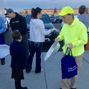 A group of people are distributing Thanksgiving meals from their vehicles, symbolizing community involvement and support, possibly related to a Las Vegas personal injury law firm's philanthropic activities.