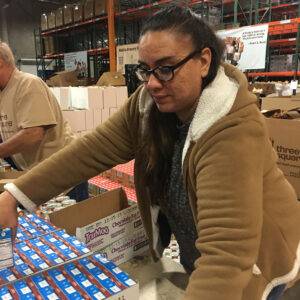 Image shows a woman volunteering at a food bank, packing chocolate milk cartons, symbolizing community support after personal injury in Las Vegas.