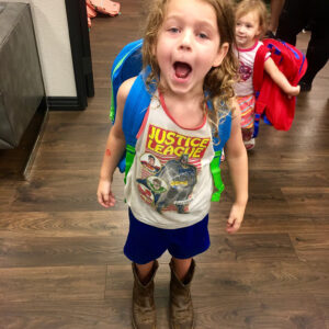 A young girl with a scraped arm wearing a Justice League shirt and cowboy boots, symbolizing the vulnerability of children and the need for justice after an accident, perfect for a personal injury law firm in Las Vegas.