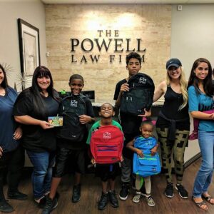 Las Vegas personal injury law firm The Powell Law Firm posing with children and backpacks for community outreach.