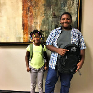 Two smiling children with backpacks, representing the families we help recover compensation after a personal injury in Las Vegas.