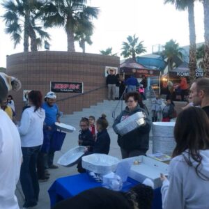 Outdoor scene in Las Vegas with palm trees, tents, and people gathering around a table, possibly for a charity event, supporting community well-being related to personal injury in Las Vegas.