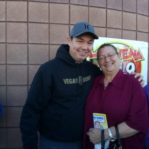 Las Vegas born attorney posing with a happy client, holding a safety activity book, indicating the firm's commitment to safety and personal injury claims.
