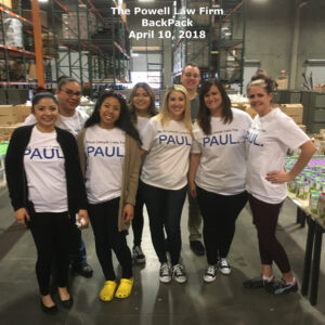 Staff members from a Las Vegas personal injury law firm pose for a photo at a community outreach event, surrounded by food donations, highlighting their commitment to the community.