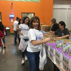 Volunteers from a Personal Injury Law Firm in Las Vegas packing food donations, including juice and canned goods, at a food bank, demonstrating their commitment to community support.