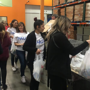 Las Vegas personal injury law firm volunteers at a local charity, with employees wearing branded t-shirts and handing out grocery bags, showing community involvement and support.