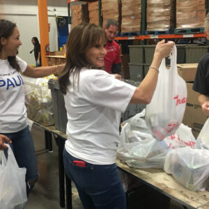 Volunteers from a Las Vegas law firm, likely specializing in personal injury, are seen packing food items into bags at a local food bank, showcasing their commitment to the community.
