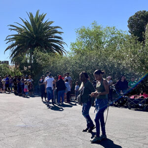 A diverse crowd of people, including families with strollers and wagons, are lined up on a sunny Las Vegas street, possibly awaiting an event or service; this image could represent a community event highlighting the law firm's involvement and support for those affected by personal injury.