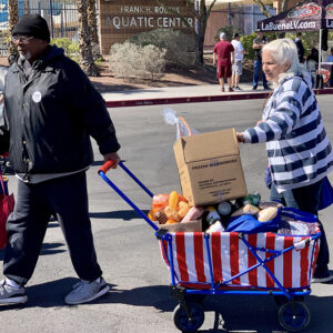 Two elderly people pulling wagons filled with food and supplies at a community event in Las Vegas, highlighting support for vulnerable individuals who might need assistance after a personal injury.