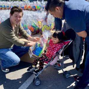 A Las Vegas law firm member hands an Easter basket to a child in a stroller, showcasing community involvement and support for children who may need personal injury assistance.