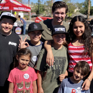 Outdoor photo of a Las Vegas personal injury lawyer with a diverse group of smiling children wearing stickers from his law firm, promoting community support and local engagement in Las Vegas.