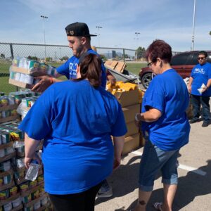 Employees of a Las Vegas Personal Injury Law Firm volunteer at a food drive, stacking canned goods and juice boxes, demonstrating their commitment to community support and helping those in need.