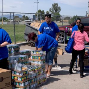 Volunteers from Paul Law Firm, a personal injury law firm in Las Vegas, are shown at a local food bank, loading and sorting canned goods and cereal boxes for those in need.