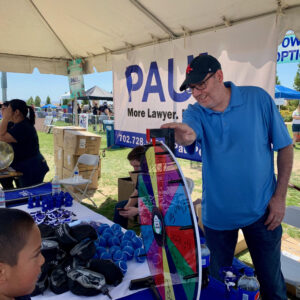 Las Vegas personal injury law firm engages with the community at an outdoor event, featuring a prize wheel and giveaways, promoting their legal services.