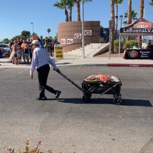 A crowded outdoor event in Las Vegas shows an elderly man pulling a wagon loaded with goods, suggesting potential personal injury risks in public gatherings.