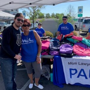 Law firm event in Las Vegas providing backpacks to the community, promoting "More Lawyer, Less Fee" for Personal Injury cases.