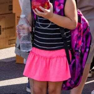 A young girl with a backpack, water, and an apple, representing the innocence and future that a Las Vegas personal injury lawyer aims to protect in cases involving children's injuries.