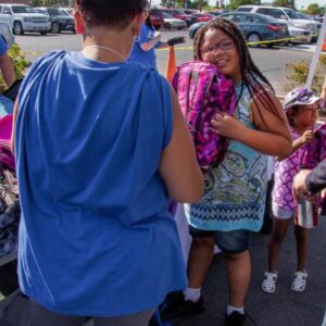 A Las Vegas personal injury law firm participates in a community event, providing school supplies like backpacks to local children, with the Las Vegas strip visible in the background.
