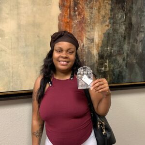 Smiling woman in Las Vegas holding a gift bag from her personal injury lawyers, showcasing positive client experience.