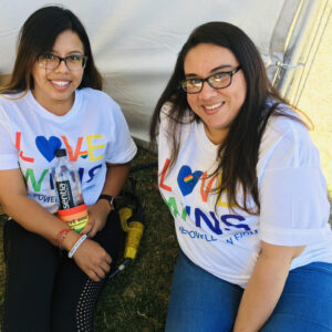 Two smiling women wearing "Love Wins" t-shirts, supporting LGBTQ+ rights and promoting inclusivity for personal injury clients in Las Vegas.