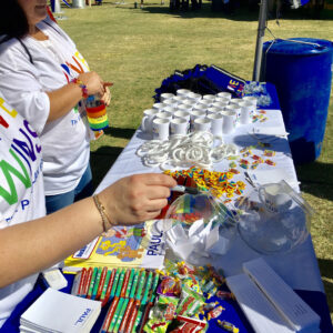 Outdoor booth at a Las Vegas community event featuring a law firm promoting personal injury services with giveaways like mugs, wristbands, and candy, highlighting their local presence and commitment.
