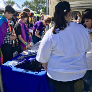 A bustling community event featuring individuals gathered around a booth, promoting inclusivity and support, representing a personal injury law firm's commitment to Las Vegas values and community well-being.