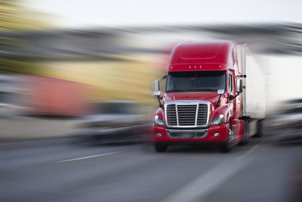 Blurred image of a red semi-truck speeding on a highway, symbolizing potential dangers and the need for legal representation for personal injury cases in Las Vegas.