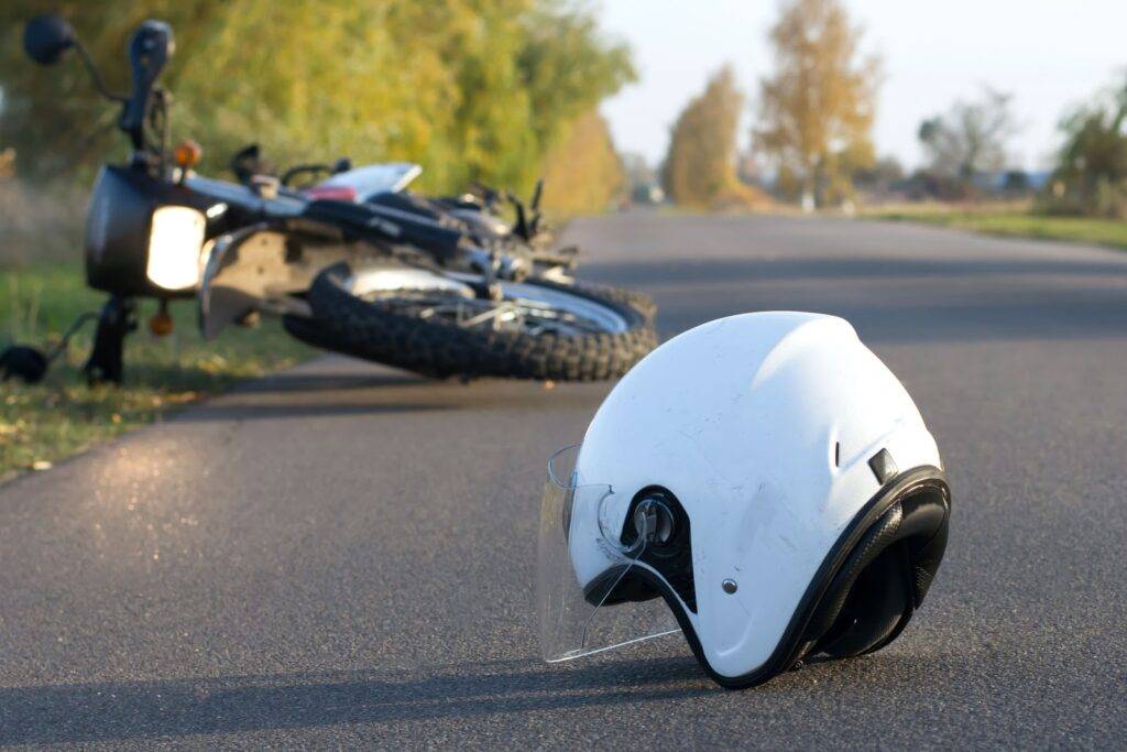 Image shows a motorcycle accident scene with a damaged helmet lying on the road, representing personal injury and the need for legal help in Las Vegas.