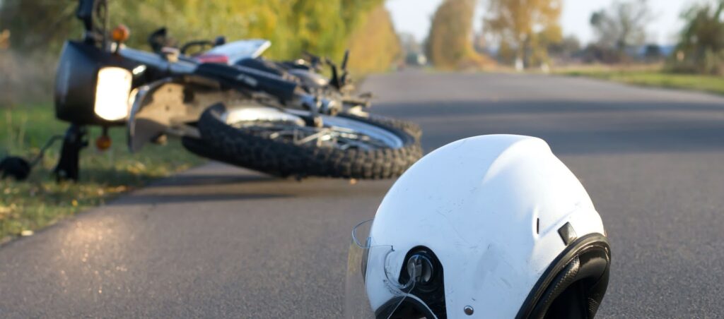 Image shows a motorcycle accident scene with a damaged helmet lying on the road, representing personal injury and the need for legal help in Las Vegas.