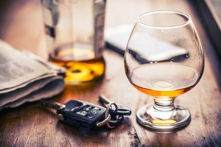 A close-up image shows a glass of amber liquid beside a bottle and car keys, symbolizing the dangers of drunk driving and potential personal injury cases, relevant to a Las Vegas law firm.