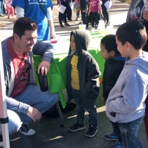 Man interacts with children at a community event, possibly sponsored by a Las Vegas personal injury law firm promoting safety and community engagement.