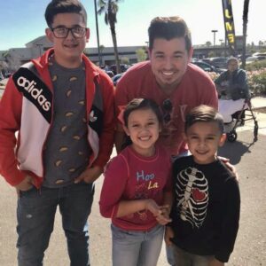 A smiling personal injury lawyer poses with three smiling children and an elderly woman in Las Vegas, highlighting the firm's dedication to the community and commitment to helping families affected by injuries.