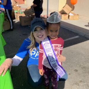 Smiling lawyer poses with "Little Miss Western" at a community event in Las Vegas, showcasing the law firm's dedication to the local community and family values.